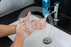 Man is washing his hands in a sink sanitizing the colona virus for sanitation and reducing the spread of COVID-19 spreading throug