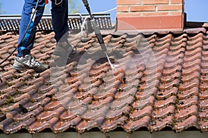 Man is washing the roof with a high pressure washer