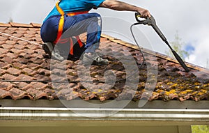 Man is washing the roof with a high pressure washer