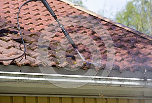 Man is washing the roof with a high pressure washer