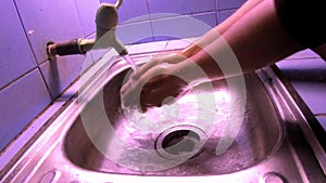 A man washing their hands with antiseptics, at night with white lights, before going to sleep to maintain cleanliness and prevent