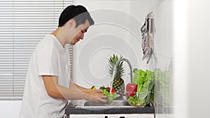 Man washing vegetables in the sink in the kitchen at home