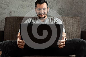 A man watches an adult video on a laptop while sitting on the couch. The concept of porn, men`s needs, pervert, lust, desire,