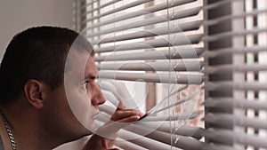 The man watches through the blinds, the man spies on people