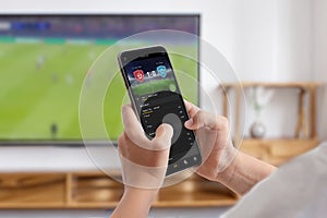 Man watches a soccer match on TV and follows online betting on his phone