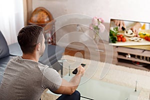 Man watching cooking tutorial in TV photo