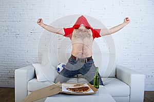 Man watching football game on tv in team jersey celebrating goal crazy happy jumping on sofa