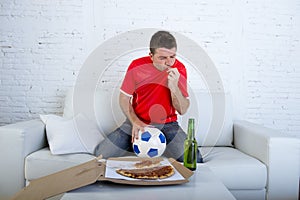 Man watching football game on tv in team jersey celebrating goal crazy happy jumping on sofa