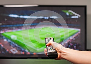 Man watching football match on television, the remote control in hand