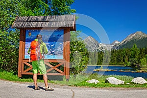 Man watching map of mountain trails by lake