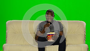 Man watching movie on couch and eating popcorn. Green screen