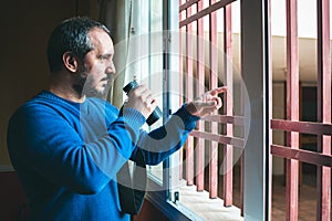 Man watching the neighbors through the window during quarantine