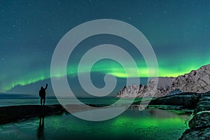 Man watching the northern lights, Aurora Borealis, Devil Teeth mountains in the background, Tungeneset, Senja, Norway