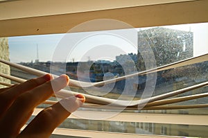 Man watching through plastic blinds windows to the street.