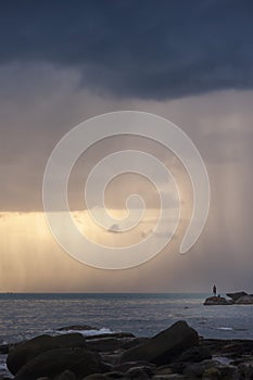 Man watching rainstrom out at sea