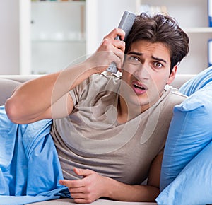 Man watching tv from bed holding remote control unit