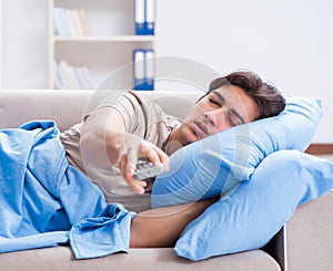 Man watching tv from bed holding remote control unit