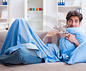 Man watching tv from bed holding remote control unit