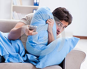 Man watching tv from bed holding remote control unit