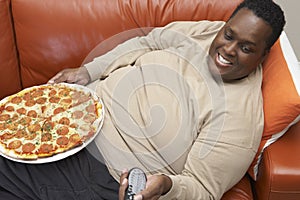 Man Watching TV With Pizza On Lap