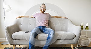 Man watching TV on the sofa at home with remote control