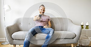 Man watching TV on the sofa at home with remote control