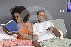 Man Watching TV While Woman Reading Novel photo