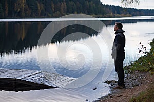 Man watching on the water of lake standing alone on the beach.