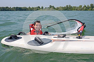 Man in water next to windsurfing board