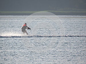 Man water skiing on the sea at sunset near the green beach