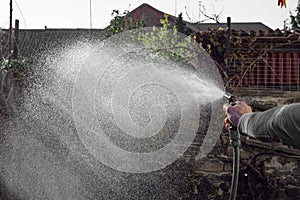 Man watering backyard lawn using hosepipe