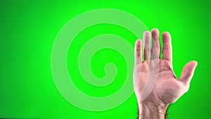 a man waves his hand on a green background hand close-up and then shows the class thumb up Male hand gesture isolated at