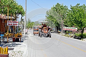 A man waving as he drives a red tractor down a road