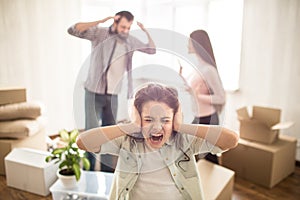 Man is waving with has hands and talking about eamotional stuff with his wife. Their child is holding her ears closed