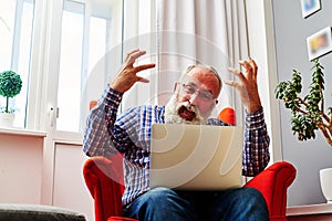 Man waving his arms and shouting at a laptop