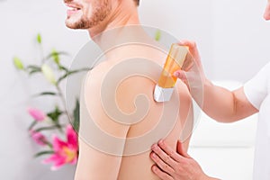 Man at waxing hair removal in beauty parlor photo