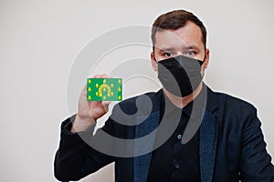 Man wear black formal and protect face mask, hold Rutland flag card isolated on white background. United Kingdom counties of photo