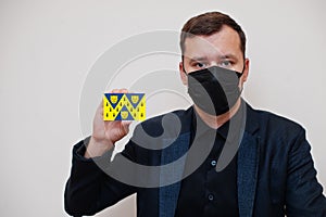 Man wear black formal and protect face mask, hold Shropshire flag card isolated on white background. United Kingdom counties of