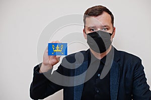 Man wear black formal and protect face mask, hold Suffolk flag card isolated on white background. United Kingdom counties of