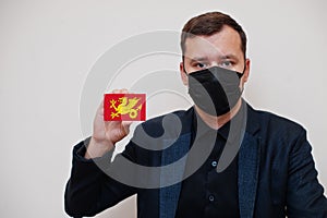 Man wear black formal and protect face mask, hold Wessex flag card isolated on white background. United Kingdom territories of