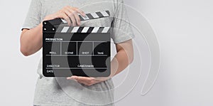A man wear gray t-shirt and hand is holding black Clapper board or movie slate. it use in video production or cinema industry.It