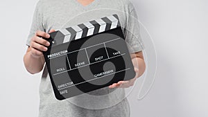 A man wear gray t-shirt and hand is holding black Clapper board or movie slate. it use in video production or cinema industry.It