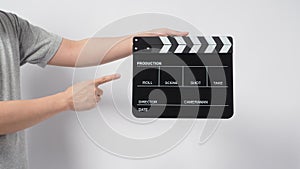 A man wear gray t-shirt and hand is holding black Clapper board or movie slate. it use in video production or cinema industry.It