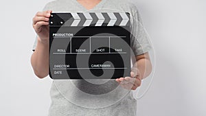 A man wear gray t-shirt and hand is holding black Clapper board or movie slate. it use in video production or cinema industry.It