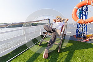 Man wear hat and sunglasses. He lie on sunbeds in the cruise ship