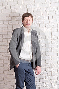 Man weared in suit stands near brick wall