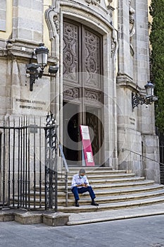 A man wearing an anti covid-19 mask sitting on the steps of the BasÃÂ­lica pontificia de San Miguel, Madrid