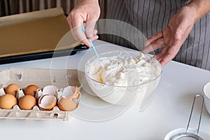 man wearing apron cooking tiramisu at kitchen