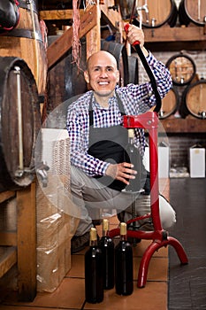Man wearing apron using bottle corking apparatus