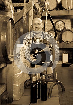 Man wearing apron using bottle corking apparatus